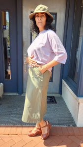 Woman standing in front of a door with a hat a light-colored outfit.